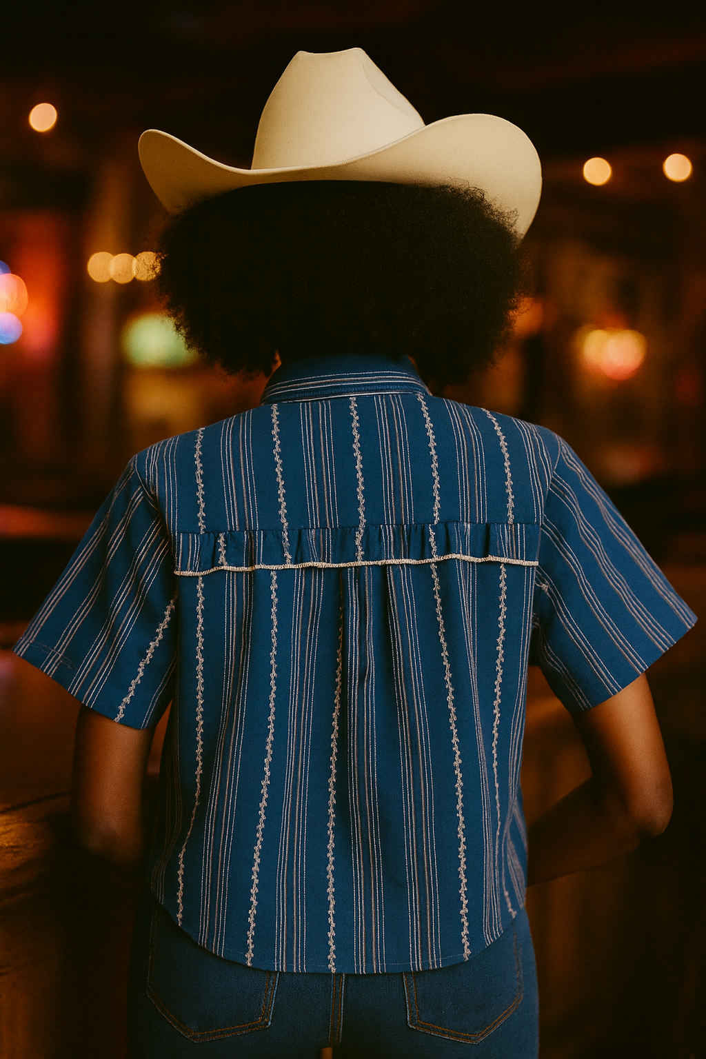 Person wearing a blue striped shirt and white cowboy hat with a blurred background